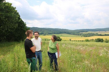 Drei Menschen stehen auf einer Wiese und unterhalten sich zum Betriebsplan Natur.